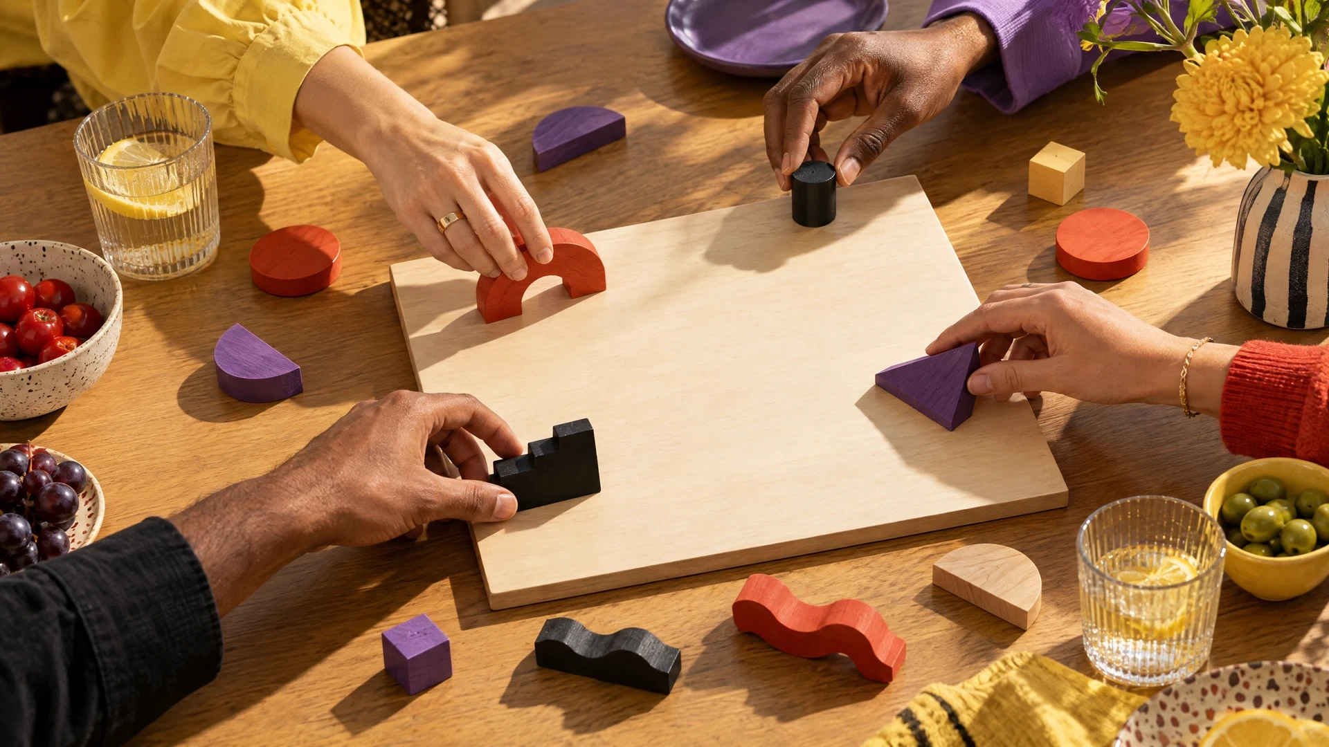 Hands placing abstract wooden pieces around an unmarked board
